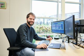 Systeembeheerder lachend achter de computer